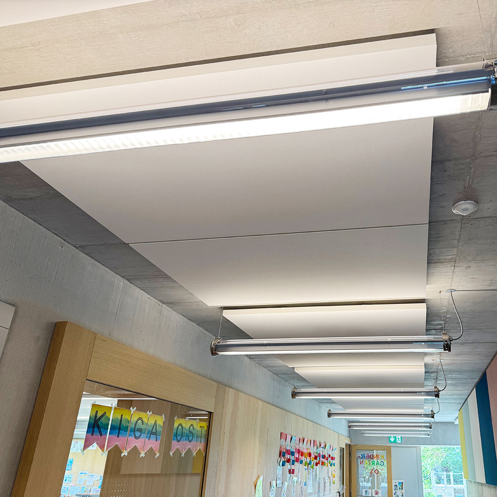 Panneaux incombustibles NoFlame Solo 6 Panneaux de plafond ininflammables à surface étanche installés dans un couloir et une issue de secours d'un établissement scolaire afin d'améliorer l'acoustique des salles de classe