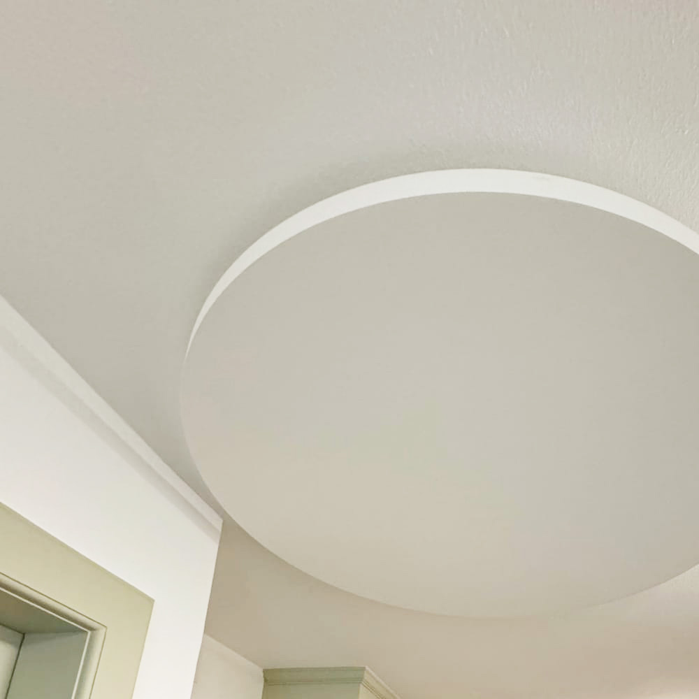 Panneaux incombustibles NoFlame Solo 10 Un grand panneau acoustique rond et ininflammable, monté à fleur du plafond texturé d'une salle de restaurant