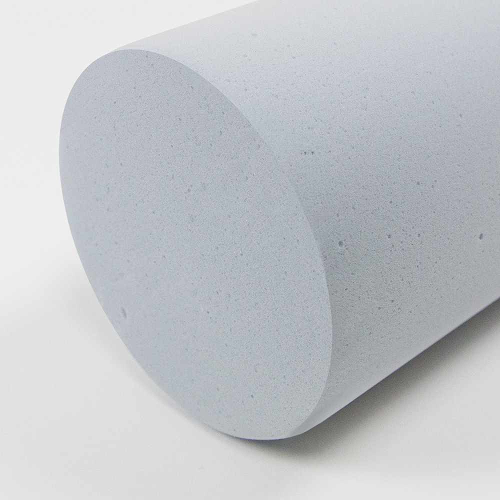 Absorbeur cylindrique acouFoam NoFlame* 1 Gros plan sur la face avant et l'enveloppe d'un absorbeur cylindrique gris ininflammable, présentant une structure en mousse à pores ouverts, mis en évidence