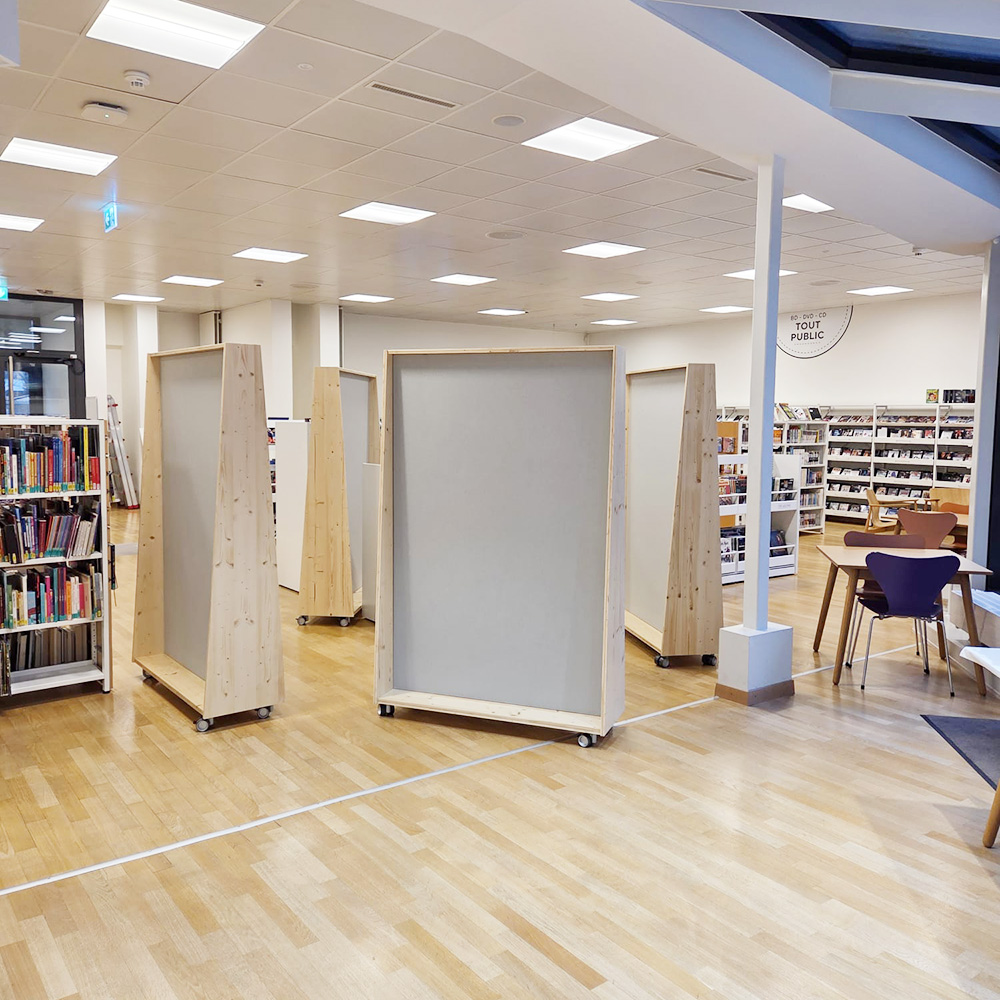 Scuola & istruzione 19 Pareti divisorie autonome con struttura in legno, dotate di pannelli fonoassorbenti grigi montati su rotelle, in una biblioteca aperta con scaffali