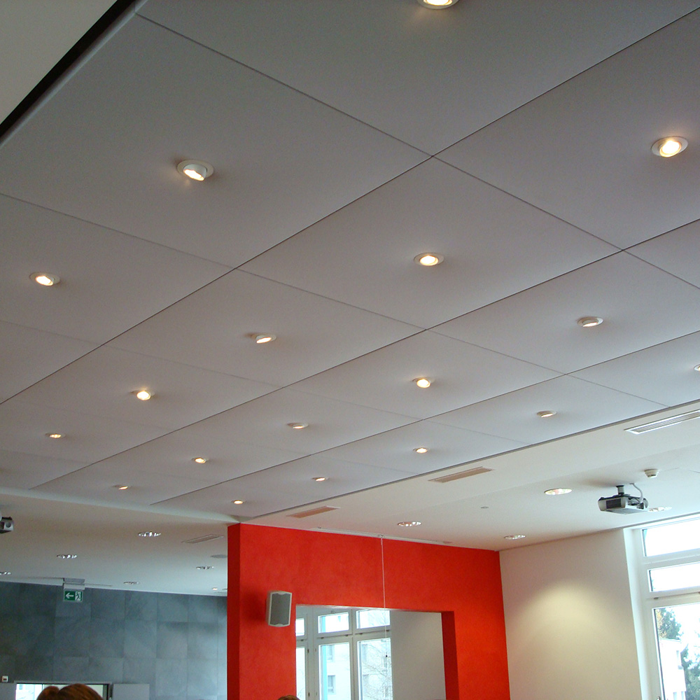 Pannelli per soffitto STRATO raggruppati 7 Des panneaux acoustiques blancs avec spots intégrés recouvrent une grande partie du plafond de la cafétéria ou du restaurant universitaire
