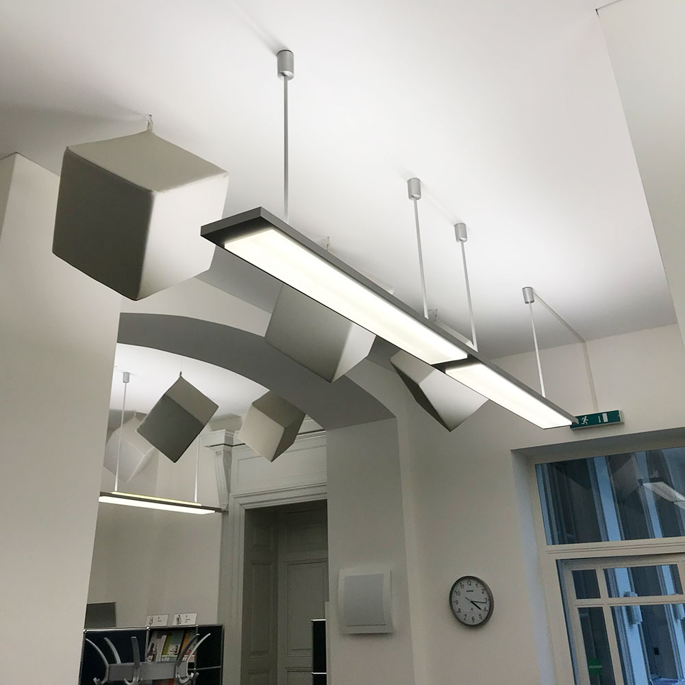 Assorbitori cubici acouFoam 5 Dei diffusori acustici cubici grigio-beige installati a sospensione nel centro informazioni del cantone di Glarona per migliorare l'acustica della sala